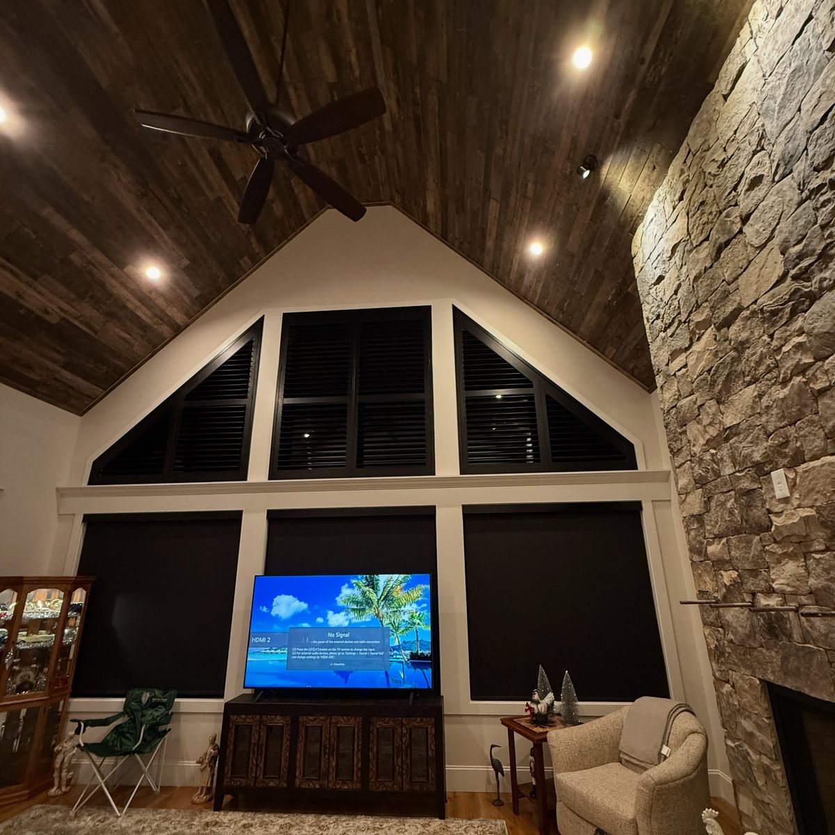 Black plantation shutters and roller shades in a vaulted great room