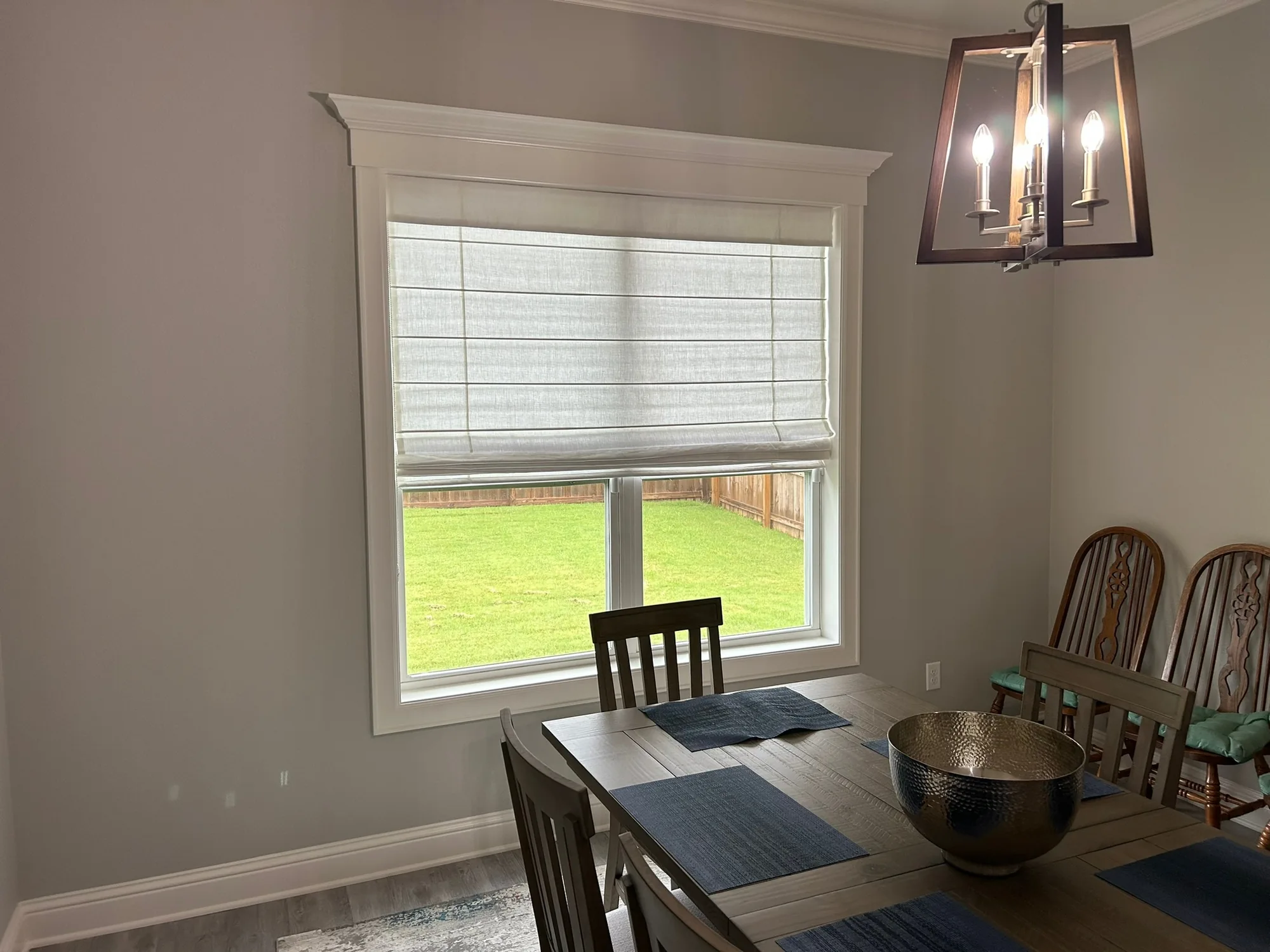 Dining room with a custom roman shade installed by Love Is Blinds